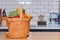 Paper bag full of fresh products from full of fresh products from grocery store or supermarket standing on wooden table