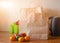 Paper bags, fresh vegetables and fruits next to a mobile phone on the table with kitchen utensil. Concept of shopping, healthy