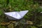 A paper boat floats through city street puddles