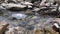 A paper boat floats in a small stream among the stones