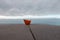 Paper boat on a railing with a background of sky and ocean