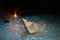 Paper boat sailing on blue water in the raging sea. Around the spray of water, night, sparklers fireworks. Symbol of struggle and