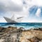 Paper boat in the sea with cliffs and sky with clouds