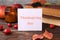 Paper card with words Thanksgiving Day near autumn leaves, berries, books and candle on wooden table, closeup