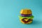 Paper cheeseburger with beef, cheese, tomato, lettuce, onion and sauce on a blue background. Copy space. Creative or art food