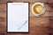 Paper clipboard and coffee on wood background with space