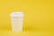 Paper coffee container with white lid on yellow background. Take