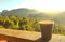 A paper coffee cup on wooden table and outdoor mountain and sunlight background