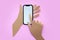 Paper craft hands hold phone. Finger touches screen. Pink background.