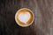 Paper cup of cappuccino coffee with beautiful latte art in the shape of heart on wooden background. Top view, copy space.