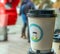 Paper cup for coffee with a funny picture on a busy city street