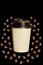 Paper cup with heartshaped coffee beans isolated on a black background