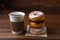 A paper cup of hot fresh brewed coffee next to a stack of fancy donuts