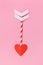 Paper cupid love arrow with heart shaped tip on pink background