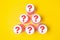 Paper cups arranged in a pyramid with a question mark on the bottom. Yellow background. Flat lay. The concept of finding a