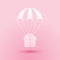 Paper cut Gift box flying on parachute icon isolated on pink background. Delivery service, air shipping concept, bonus