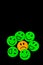 paper cutout image of green smiley faces surrounding a sad face