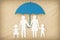 Paper family silhouette with umbrella on wooden background - Concept of family protection