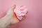 Paper heart in the palm. Crumpled paper heart in hand. Female hand holds a delicate pink heart on pink background. Heart health