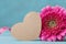 Paper heart tag and beautiful pink gerbera flower on turquoise table. Greeting card for Birthday, Woman or Mothers Day.