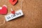 Paper hearts and note with words WE CAN HELP attached to string on cork board