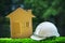 paper home out line with safety helmet on green grass field wtih blur copy space background use for real estate and land