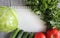 Paper leaf and composition of vegetables on grey wooden desk.