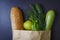 Paper package full of food on black background. Healthy food from the store. Vegetables and bread in package from the store.