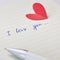 Paper page of notepad with sign I love you, pen and red paper heart