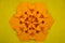 Paper quilling and origami composition. Creative orange hexagon isolated on yellow background.