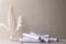 Paper rollers and white quill feathers in glass bottle on white wood table. Feathers and paper rollers against white wall with emp