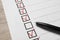 Paper sheet with checkboxes and pen on wooden table, closeup. Checklist