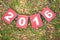 Paper sign 2016 on green grass