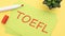 paper with text TOEFL on a yellow background with stationery