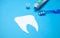 Paper Tooth with a toothbrush and toothpaste on blue background