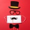 Paper top hat  mustache  sunglasses and a bowtie with medical mask on the red background. Quarantine party