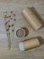 Paper tube with paper cover on wooden background with dry flax. Flat lay recycle concept. Top view. Vertical mobile