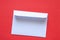 Paper white mail envelope lies on a red background close up