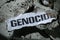 Paper with word Genocide on pieces of concrete, top view