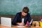 Paperwork part of teachers life. Check homework. Teacher bearded hipster with eyeglasses sit in classroom chalkboard