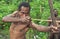 Papuan shooting arrows from a bow. Natural green jungle background