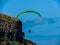 Para glider soars over the beach waves and hills at Murawai Beach Auckland New Zealand