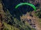 Para glider soars over the beach waves and hills at Murawai Beach Auckland New Zealand