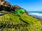 Para glider soars over the beach waves and hills at Murawai Beach Auckland New Zealand