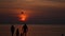 Parachute activity at tropical beach at sunset. Silhouettes of people walking on the beach and swimming in the sea. Calm