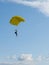 Parachuter descending with parachute against blue sky. Skydiver in the sky. People under parachute in the sky