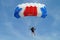 Parachuter, skydiver jumping and skydiving with blue white red colours parachute on parachuting cup, extreme sport