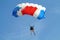 Parachuter, skydiver jumping and skydiving with blue white red colours parachute on parachuting cup, extreme sport