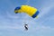 Parachuter, skydiver jumping and skydiving with blue yellow colours parachute on parachuting competition, extreme sport