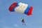 Parachuter, skydiver jumping and skydiving with red blue white colours parachute on parachuting cup, extreme sport